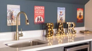 Una cocina con pileta, grifo y letras decorativas que dicen "BAR" en la encimera.