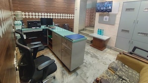 Una oficina moderna con un escritorio curvo, sillas de oficina negras, un sofá, un televisor y un dispensador de agua.