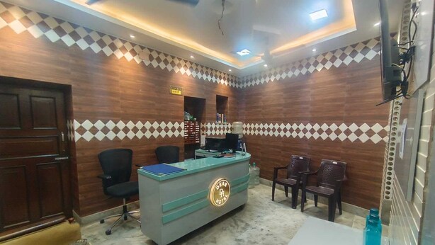 Zona de recepción con mostrador, sillas, máquina de café y pared con diseño a cuadros.