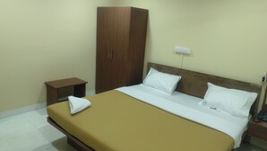 Una habitación de hotel con una cama, un armario de madera, una mesita de noche y una mesilla.