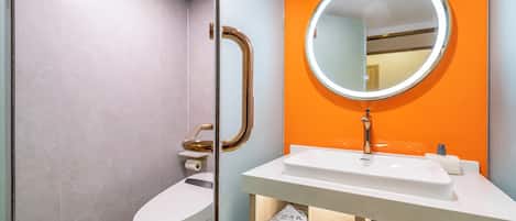Een moderne badkamer met toilet, wastafel en spiegel.