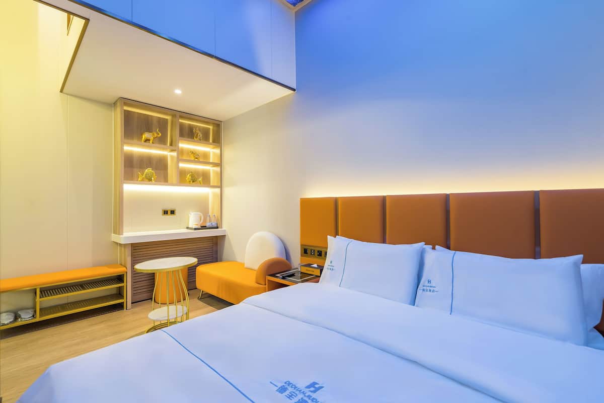 Een moderne hotelkamer met een bed, een klein bureau, een stoel en een bankje.