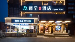 Entrada de un hotel con un letrero que dice "dequan Hotel" y otro letrero para el restaurante "LANZHOUHOUYUONIAN".