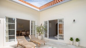 A poolside area with two wicker lounge chairs, a potted plant, and a clear blue pool. - Luxe Stunning 3BR Villa in Canggu, 8 mins to beach (Canggu)