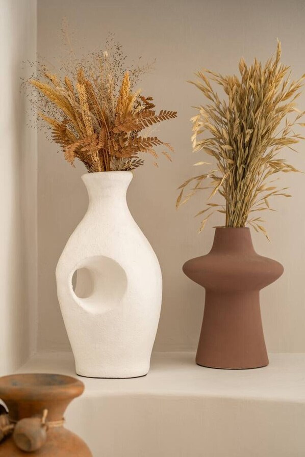 Two vases with dried plants on a shelf.