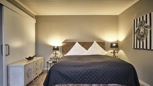 A bedroom with a bed, bedside lamps, a dresser, and a wall art piece.