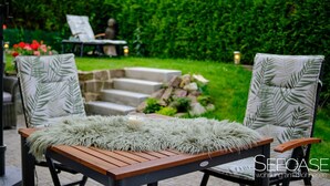 An outdoor seating area with two chairs, a table, and a green umbrella.
