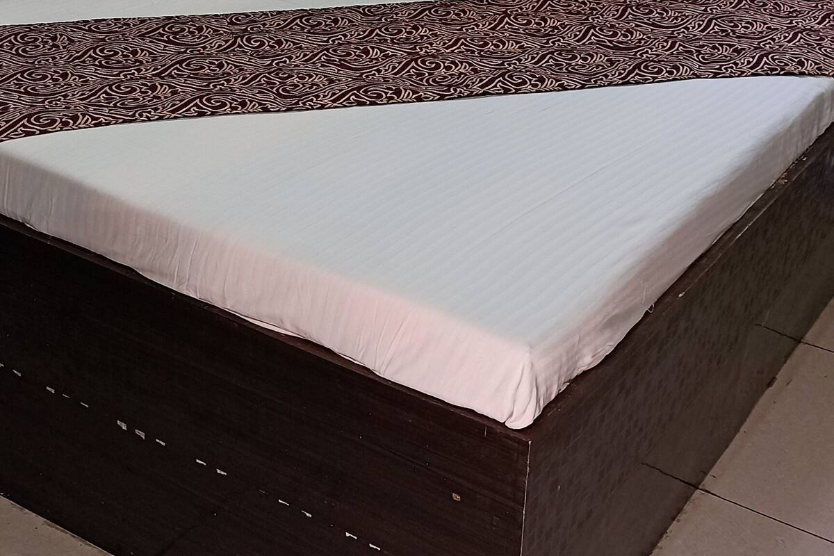 Una cama con colcha estampada, cabecera capitonada y almohadones decorativos.