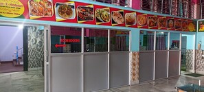 Un restaurante con un cartel de 'ROOM BOOKING', varias imágenes de comida en la pared y un suelo de baldosas.