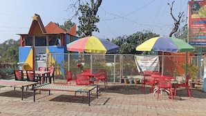 A restaurant with outdoor seating, including tables and chairs, and colorful umbrellas. - Hindustan Hotel (Gobindpur)