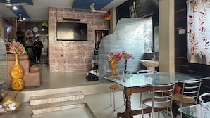 A modern living room with a TV, a fireplace, and a dining area with a glass table and chairs.