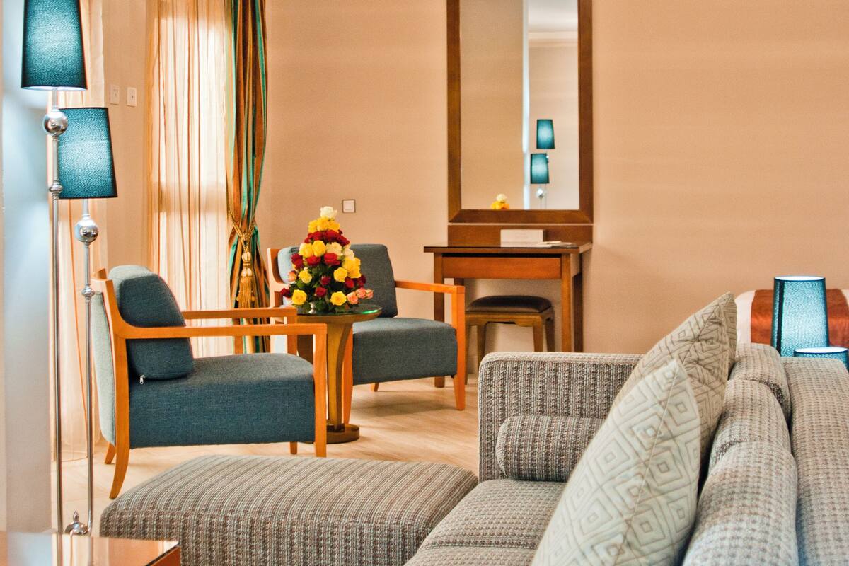 A modern living room with a sofa, chairs, a small table, and a mirror.