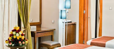 A hotel room with two beds, a desk, a chair, a lamp, and a curtain.