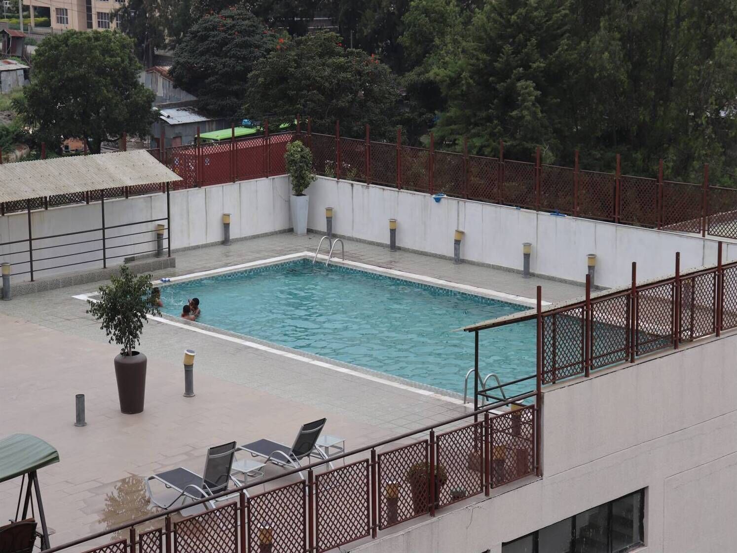 Ein Pool auf dem Dach mit Blick auf die Umgebung, darunter Bäume und Gebäude.