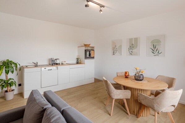 Una cocina moderna con armarios blancos, una mesa de comedor con sillas y un sofá.