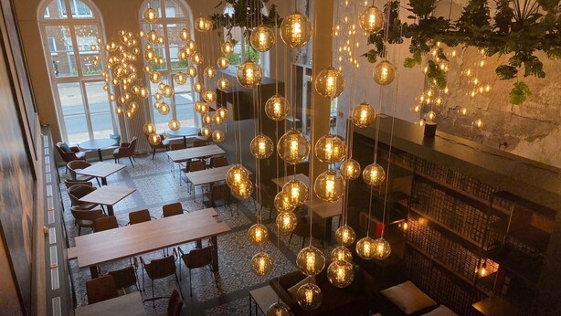 A spacious restaurant with high ceilings, hanging spherical light fixtures, and a view of the street through large windows. - Bendix weaving mill, apartment, 1-3 persons (Dülmen)