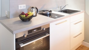A modern kitchen with white cabinets, a built-in oven, a sink, and a bowl of fruit on the countertop. - Bendix weaving mill, apartment, 1-3 persons (Dülmen)