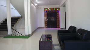 A spacious living area with a staircase, a black leather sofa, and a glass coffee table.