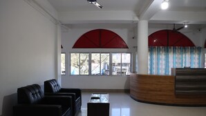 A reception area with a wooden reception desk, black leather sofas, and a glass coffee table.
