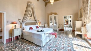 A bedroom with a four-poster bed, a canopy, a mirror, a wardrobe, and a patterned floor.
