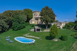 Una extensa propiedad con piscina, sillas de descanso y una torre.