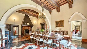 A spacious dining area with a large round table, wooden chairs, and a patterned floor.