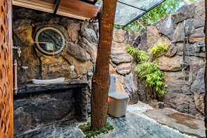 Een badkamer met stenen muren, een wastafel, een toilet en een douche.