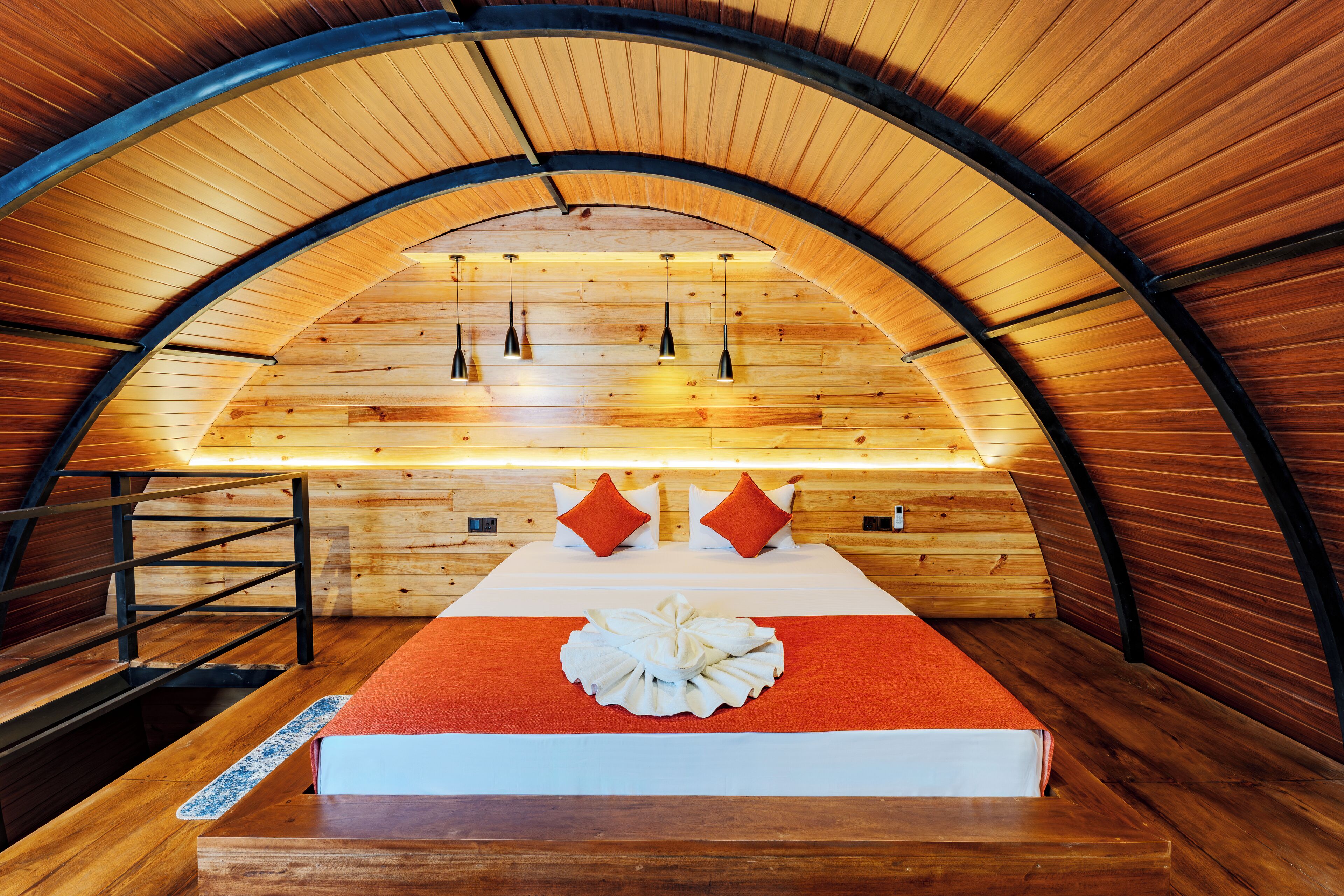 Un interior acogedor de madera con una cama, almohadas y un techo abovedado único.