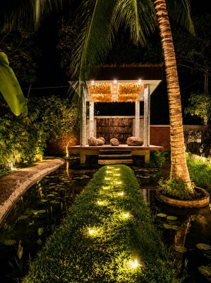 A serene outdoor seating area with a water feature, surrounded by lush greenery and palm trees. - Woodland Sanctuary  (Habarana)
