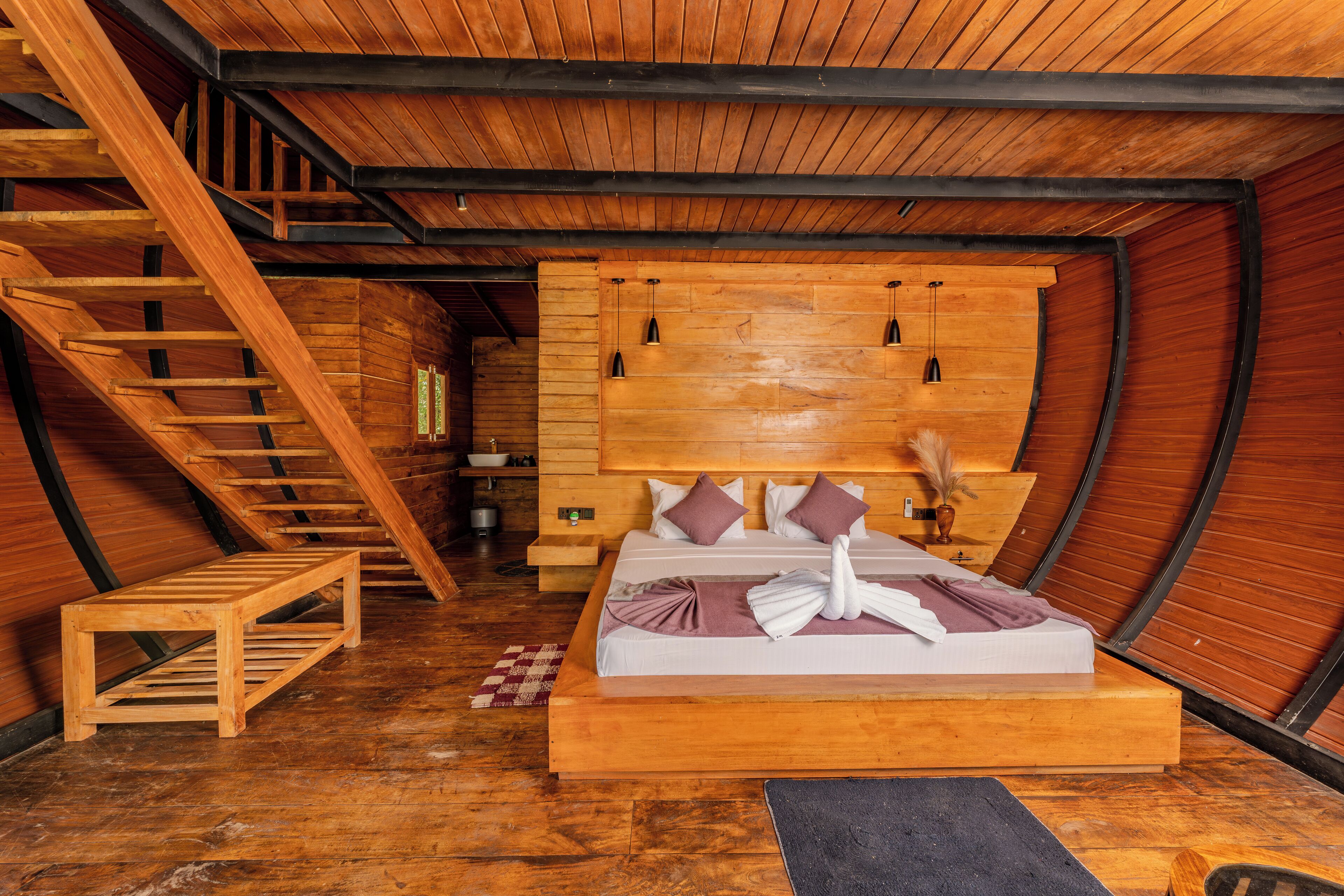 Un dormitorio con una escalera de madera, una cama con almohadas, una mesita de noche y un cabecero.
