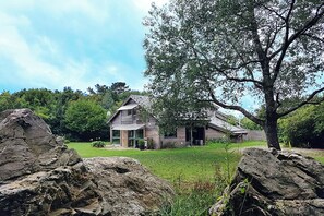 A rustic house with a sloped roof, large windows, and a stone foundation. - Le chalet breton, Enjoy your vacations in a warm and green setting (loperhet)