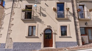Un bâtiment doté d’une entrée centrale, de nombreuses fenêtres et de balcons ornés de plantes en pot.