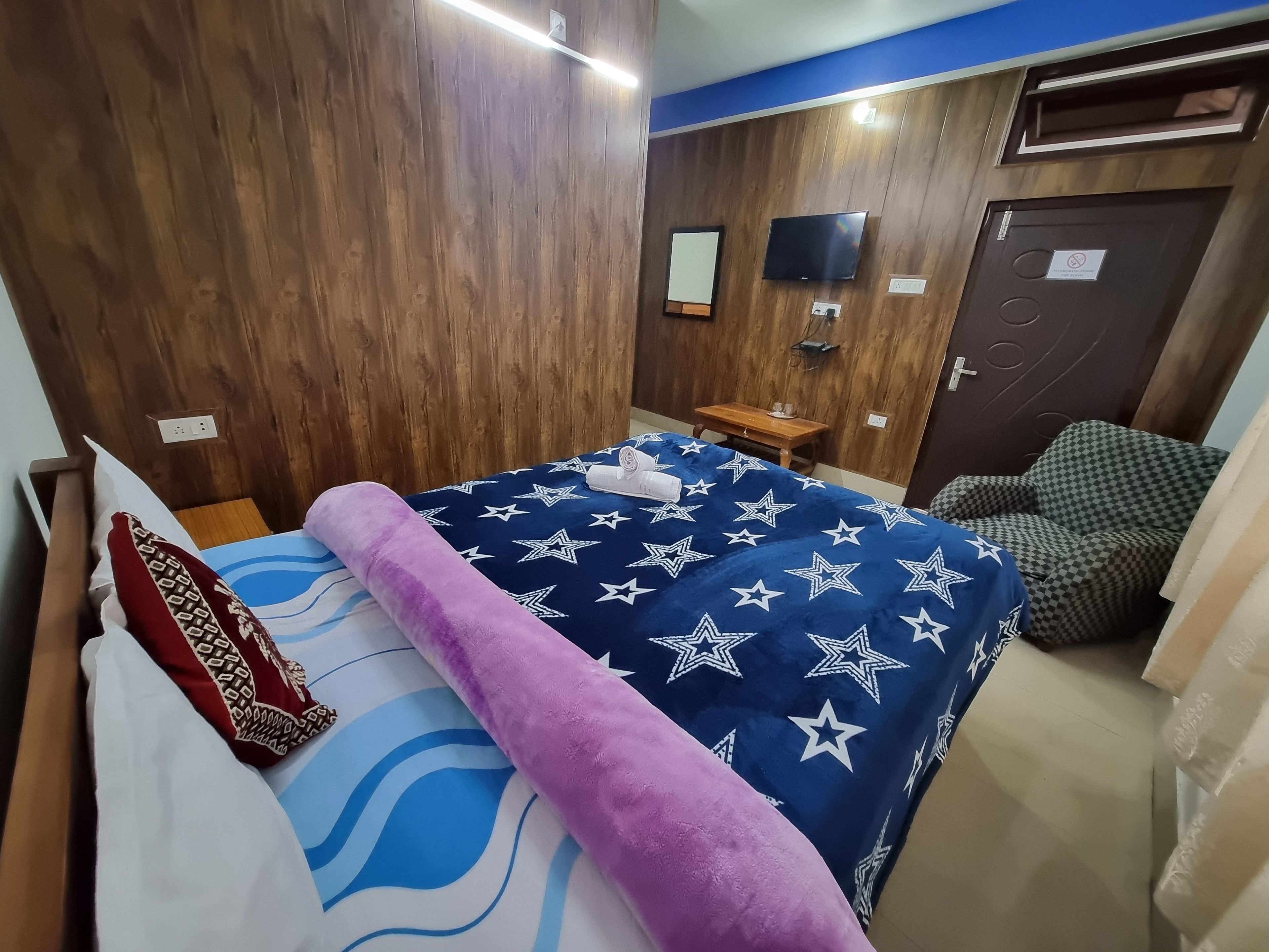 Een slaapkamer met een bed, een houten kledingkast, een televisie en een klein tafeltje.