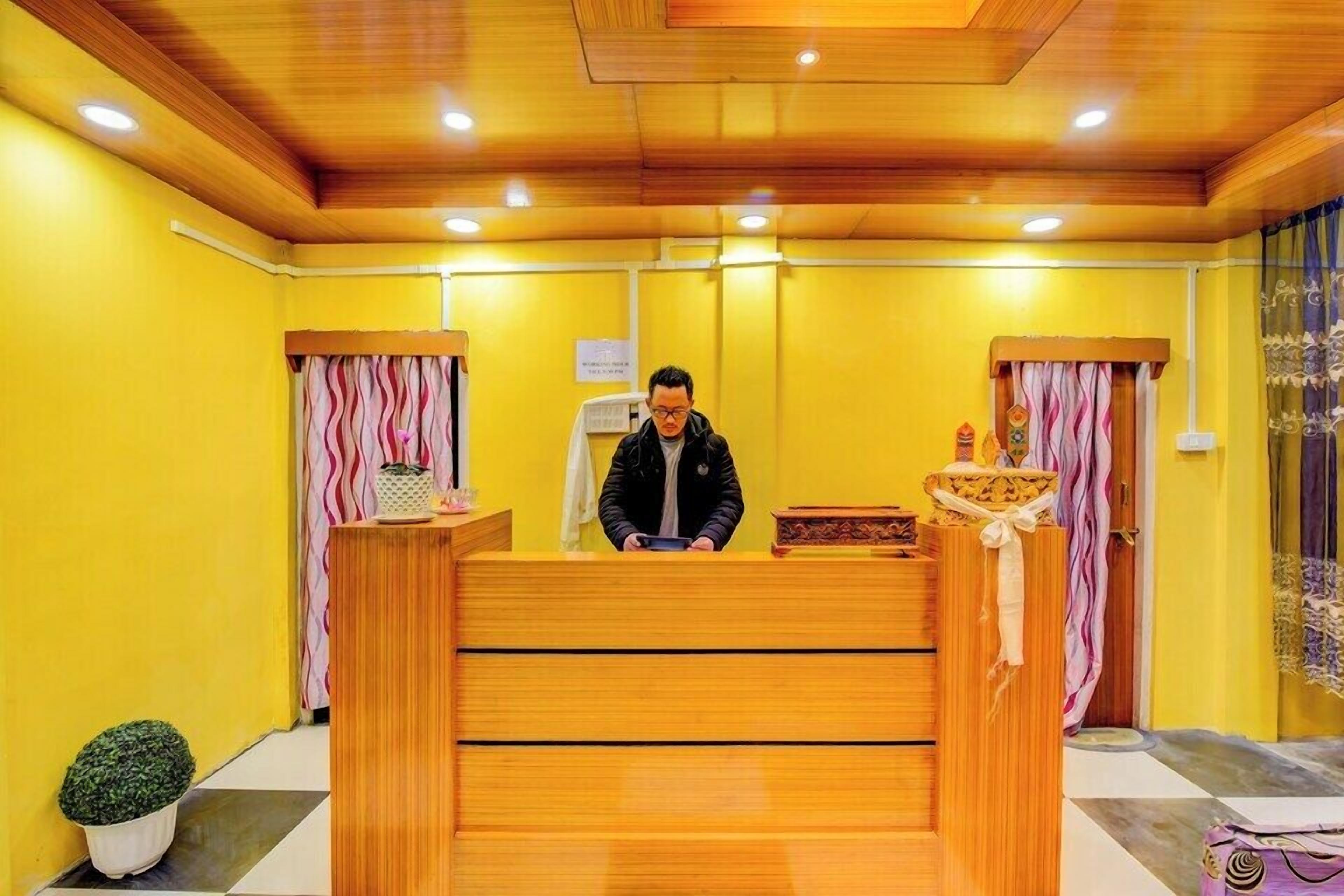 A reception desk with a wooden finish, a potted plant, and a sign on the wall.