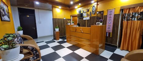 A reception area with a checkered floor, wooden reception desk, and a black door marked with the number 103.