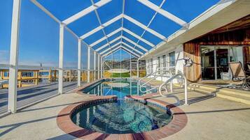 Area piscina con tetto in vetro, vasca idromassaggio e solarium con sedie.