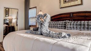 Une chambre à coucher avec un grand lit, une tête de lit en bois, une table de chevet avec une lampe, un miroir et un tableau encadré au mur.