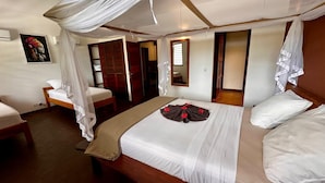 A bedroom with a bed, a bedside table, a chair, and a wardrobe. - ANKI LODGE (Nosy Be)