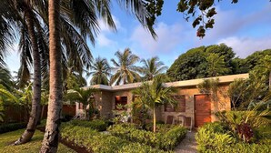 A modern villa with a stone facade, surrounded by lush tropical vegetation and palm trees. - ANKI LODGE (Nosy Be)