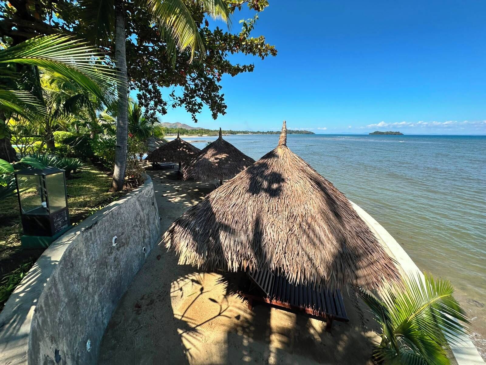 Une plage avec des parasols en chaume et une vue dégagée sur la mer.