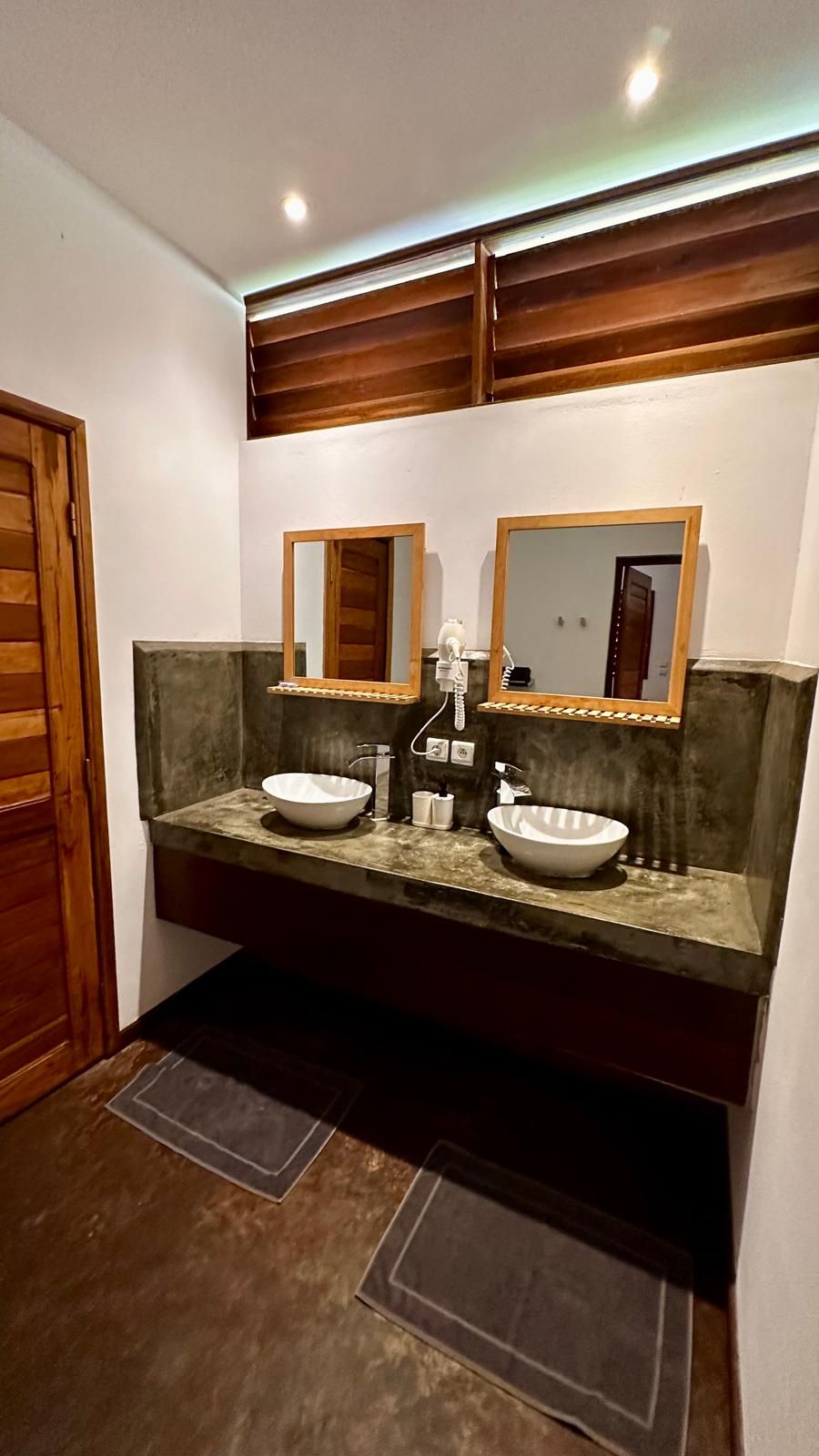 A bathroom with a double sink, wooden vanity, and a hairdryer.