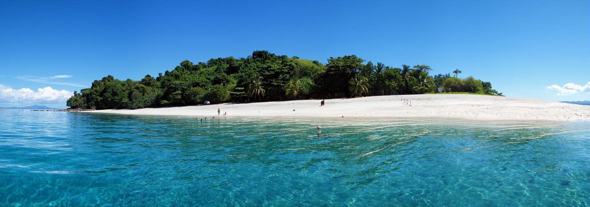 Une île tropicale aux eaux d’un bleu limpide et aux plages de sable fin.