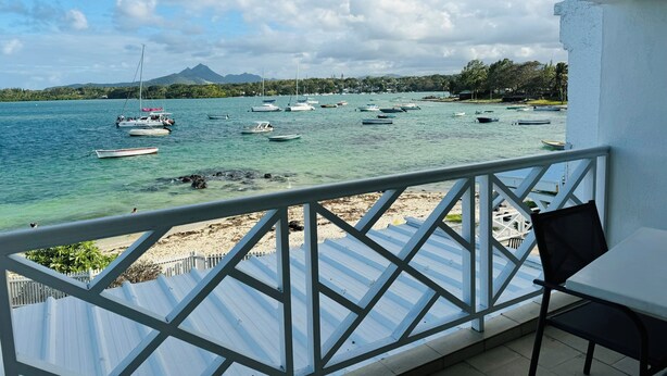 A balcony with a view of a calm sea, several boats, and a distant mountain. - Charming 2-bedroom apartment with WiFi, AC in enchanting Port Louis (Port Louis)
