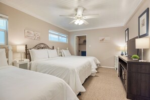 Ein Schlafzimmer mit zwei Betten, einem Deckenventilator, Nachttischlampen, einer Kommode und Bildern an den Wänden.