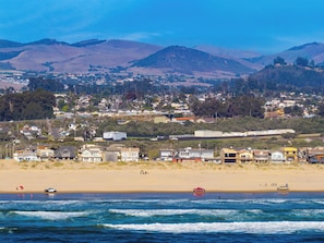 Eine Küstenstadt mit Strand, Häusern und Bergen im Hintergrund.