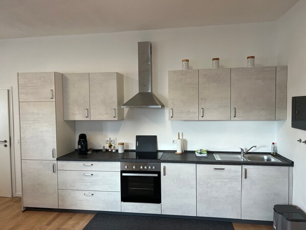 Una cocina moderna con horno integrado, cafetera y campana extractora de acero inoxidable.