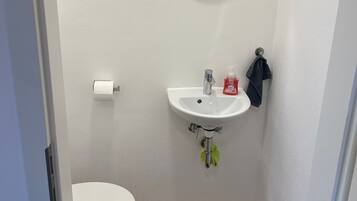 Un baño pequeño con inodoro, lavamanos y espejo.