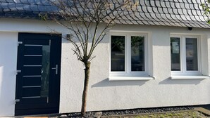 A house with a dark roof, white exterior walls, a black door, and two windows.