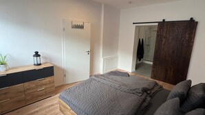 A bedroom with a bed, wooden dresser, and a mirror.