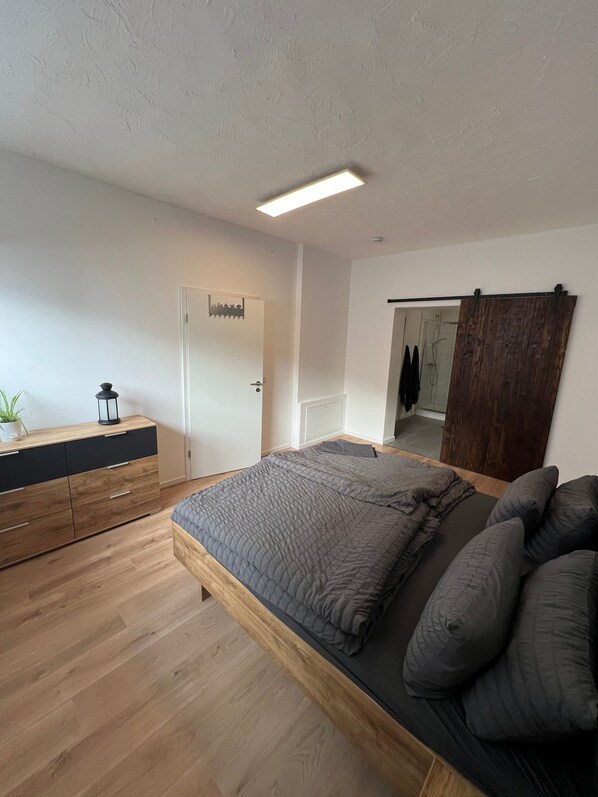 Un dormitorio con una cama, cómoda de madera y un espejo.